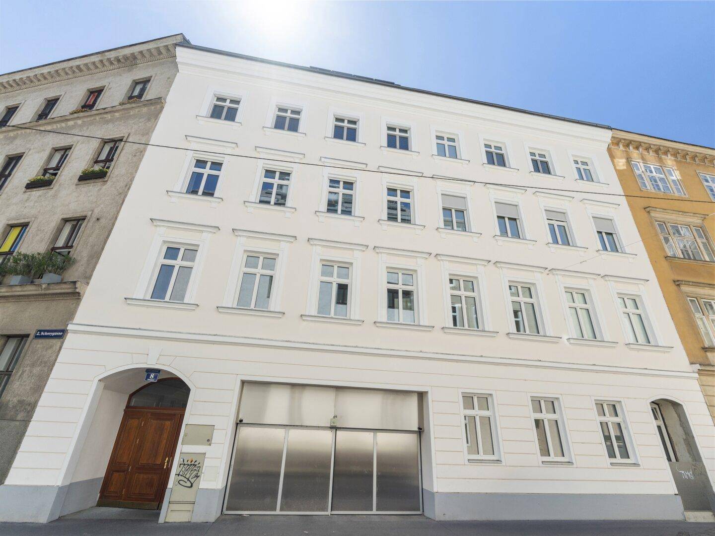 Ansicht eines gepflegten Altbaus mit moderner Garageneinfahrt in der Stadt.