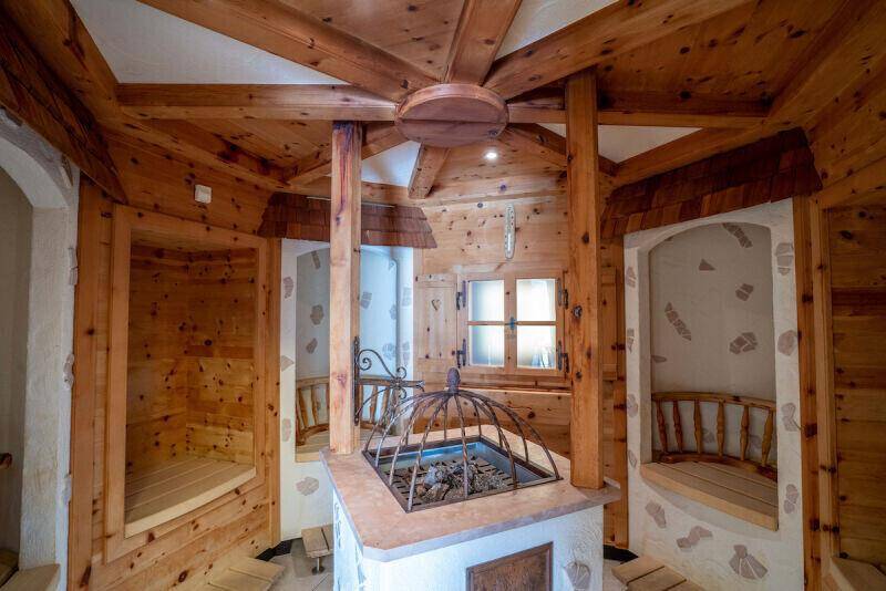 Traditionelle Holzsauna mit rustikalem Design, Holzbänken und einem zentralen Ofen, strahlt Gemütlichkeit aus.