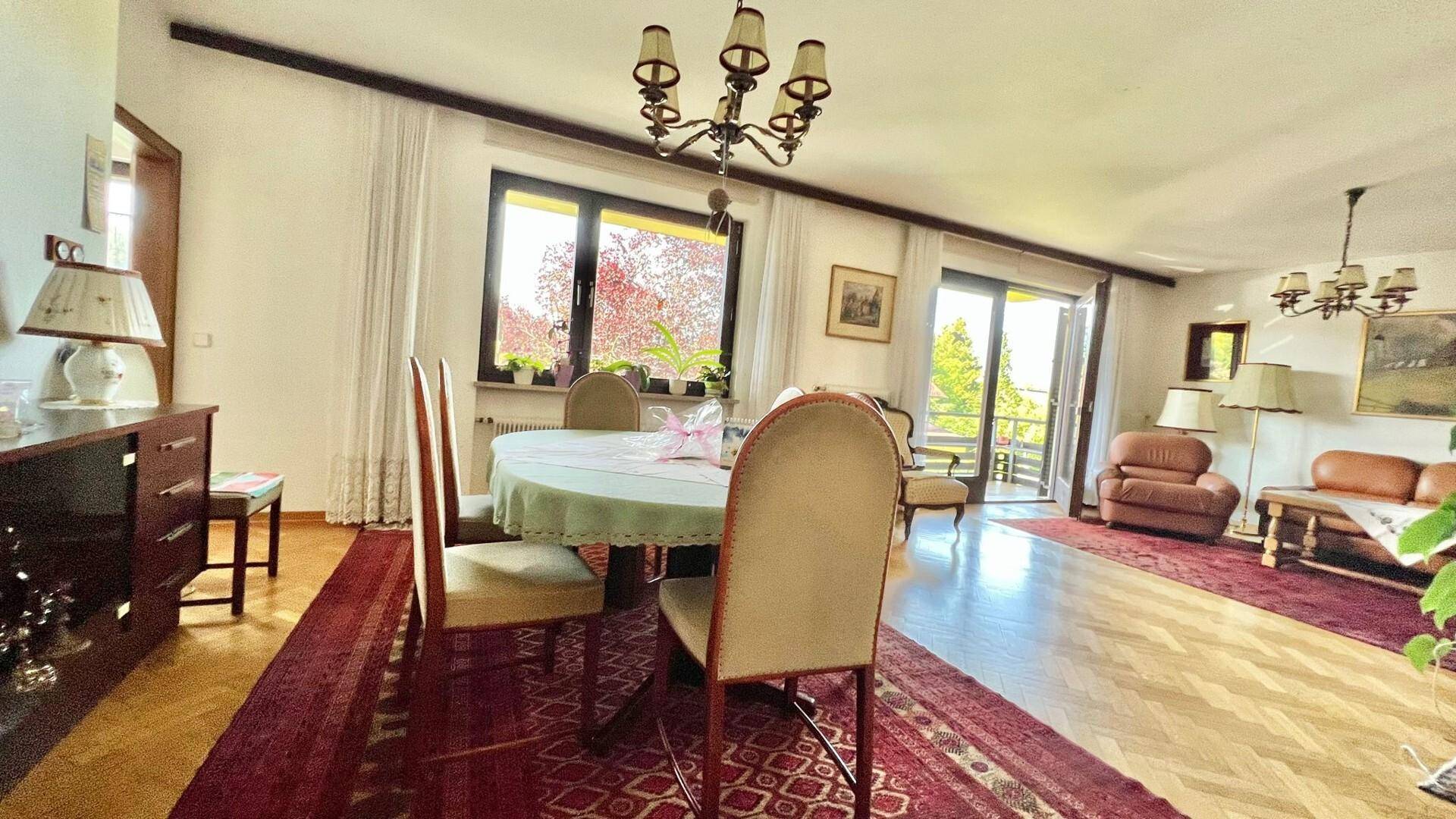 Gemütlicher Wohn-Essbereich mit Parkettboden, Esstisch und Zugang zum Balkon.