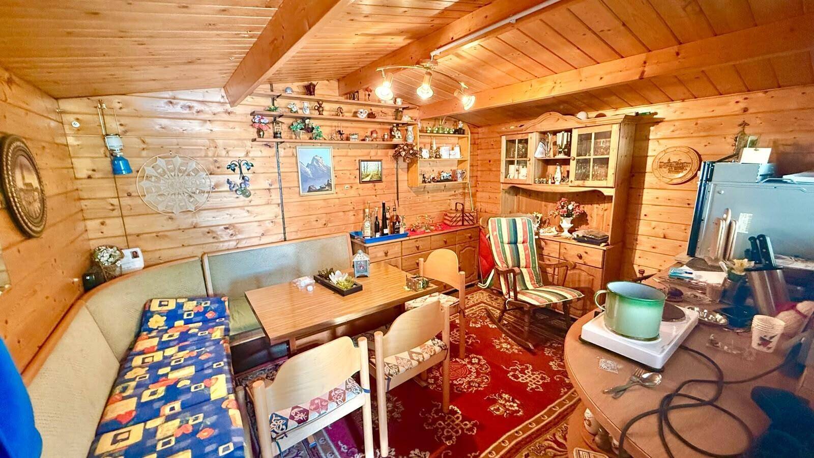 Rustikaler Essbereich in einer Holzhütte mit Holzwänden, Decke und traditionellen Möbeln.