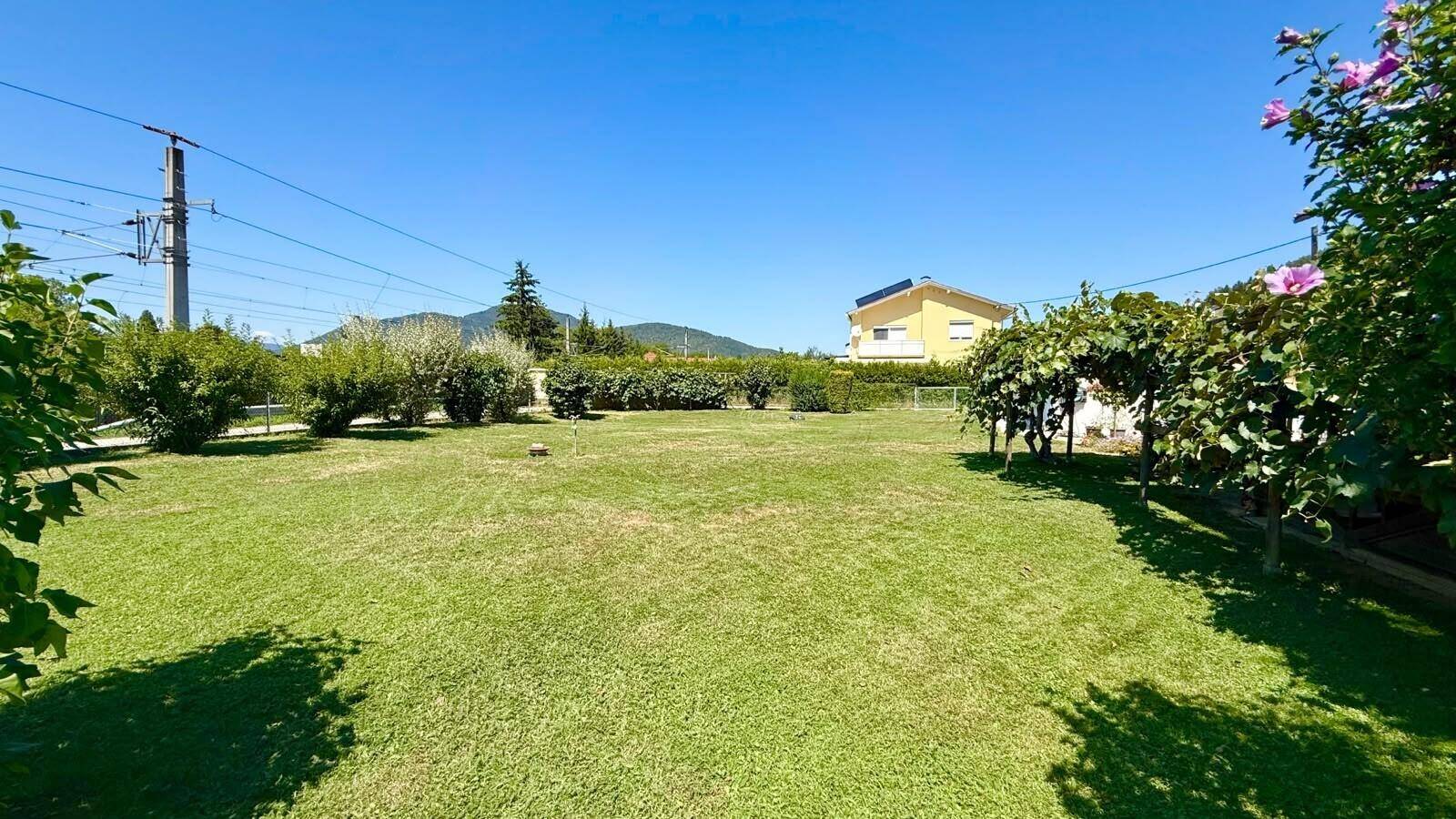 Weitläufiger Rasenbereich mit Blick auf die Berge und die umliegende Landschaft unter blauem Himmel.