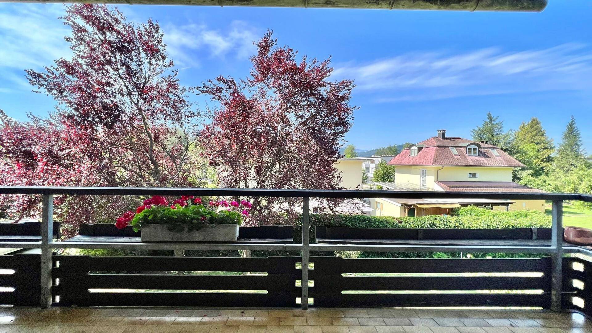 Balkon mit Blick auf die grüne Umgebung und die umliegenden Häuser.