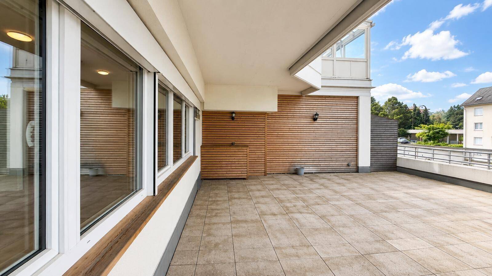 Geräumige Terrasse mit Fliesenboden und Holzverkleidung, ideal für entspannte Stunden im Freien.