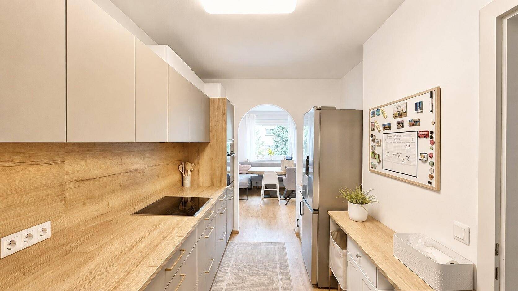 Moderne Küche mit grauen Fronten, Holzdetails und Blick in den Essbereich.