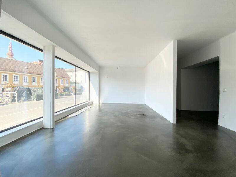 Geräumiger, heller Geschäftsraum mit großen Fenstern, die viel Tageslicht hereinlassen.