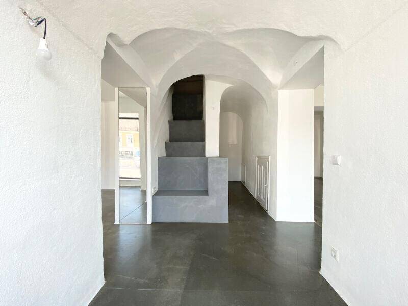 Eingangsbereich mit markanter Betontreppe und historischen Gewölbedecken.