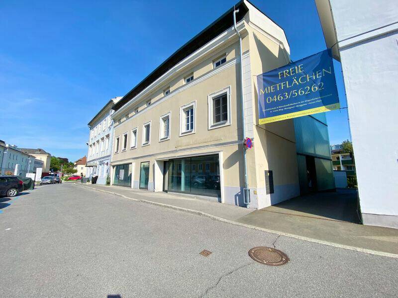 Außenansicht eines Geschäftsgebäudes mit großen Schaufenstern und einem Werbebanner.