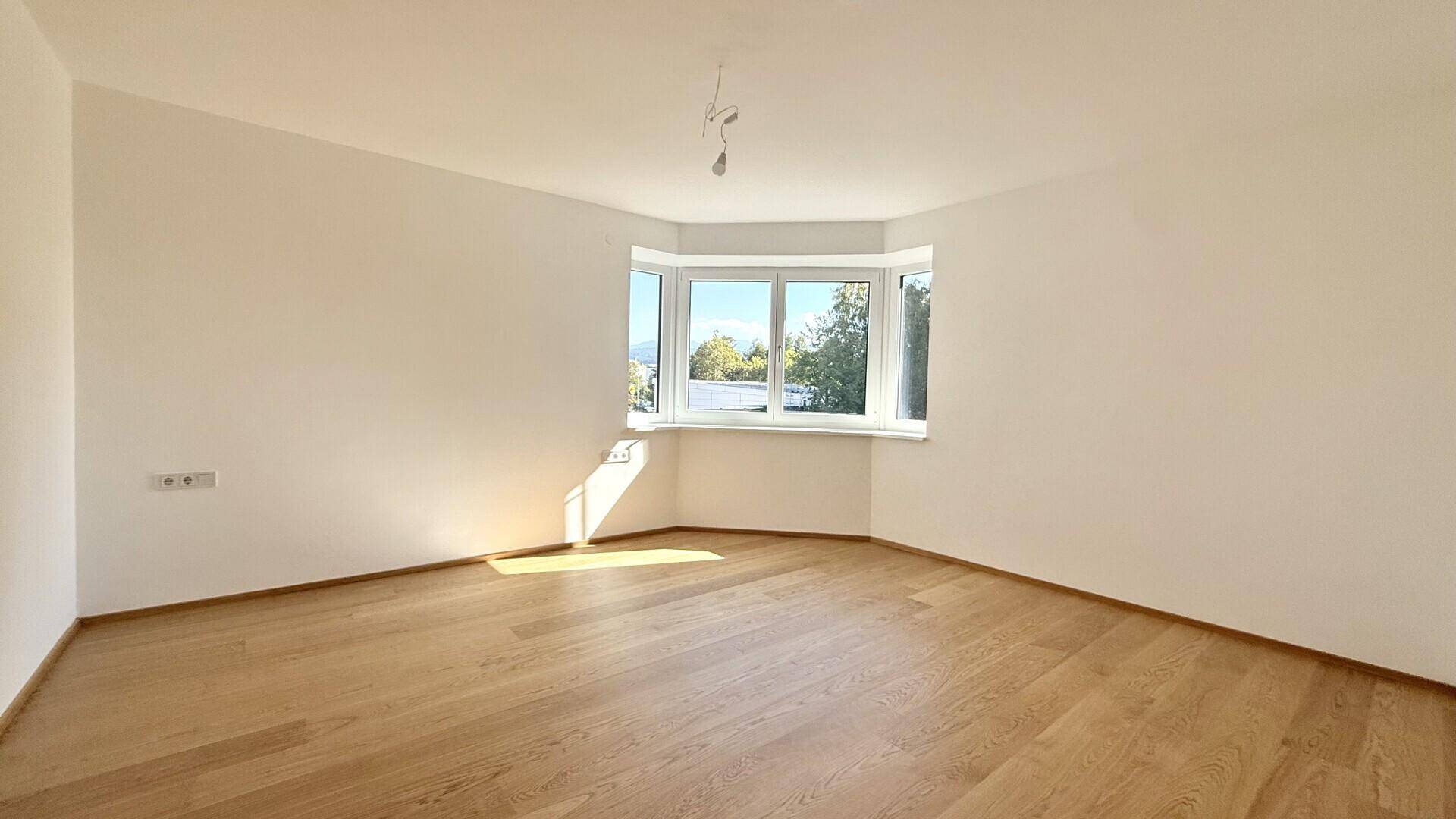 Helles Zimmer mit Holzboden und Erkerfenster, ideal als Schlaf- oder Arbeitszimmer.