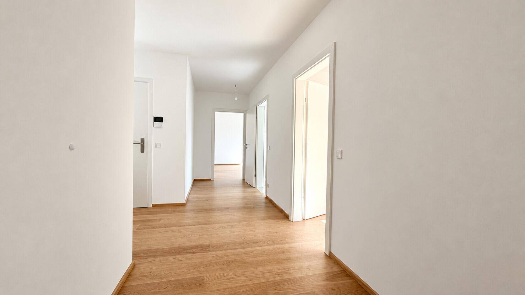 Heller Flur mit Holzboden und mehreren Türen zu den angrenzenden Zimmern.