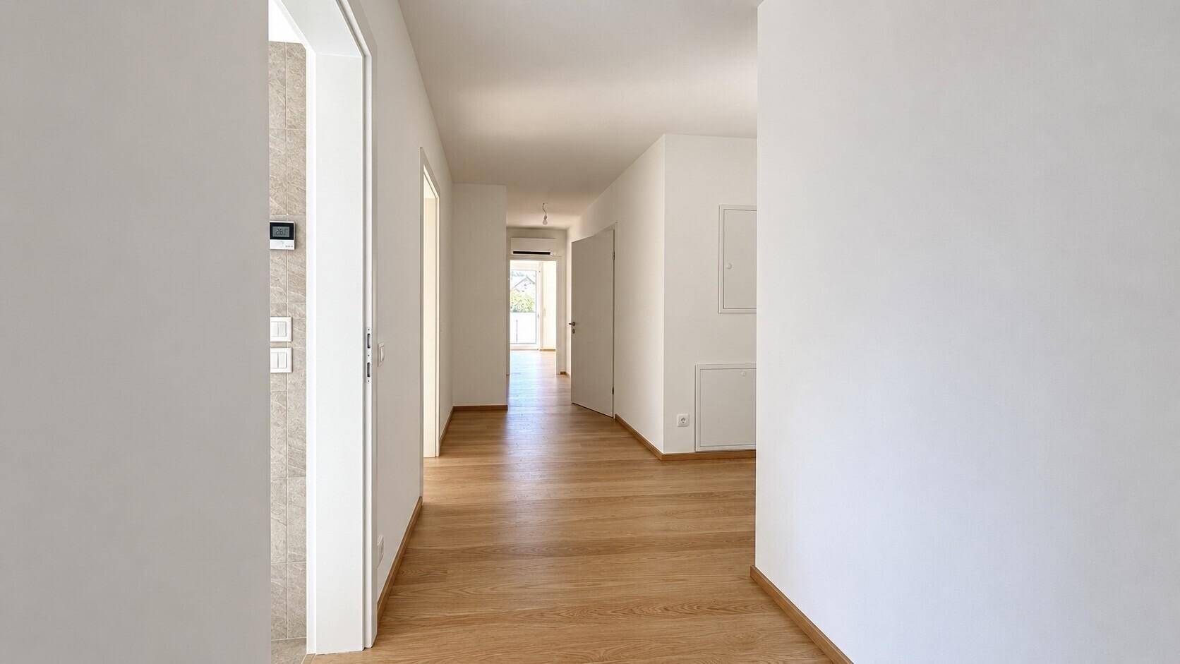 Langer, heller Flur mit Holzboden, der zu den verschiedenen Räumen führt.