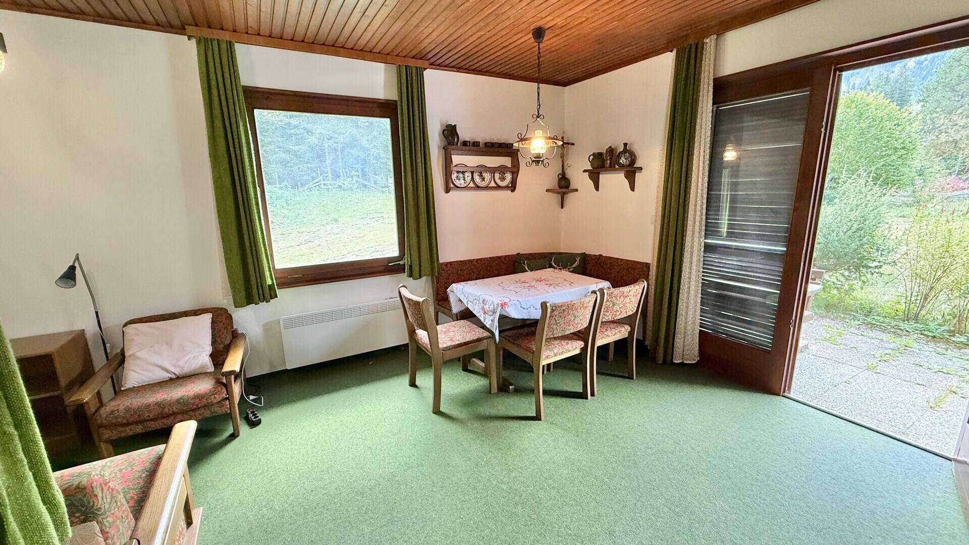 Gemütlicher Essbereich mit Eckbank und Zugang zur Terrasse, umgeben von grüner Natur.