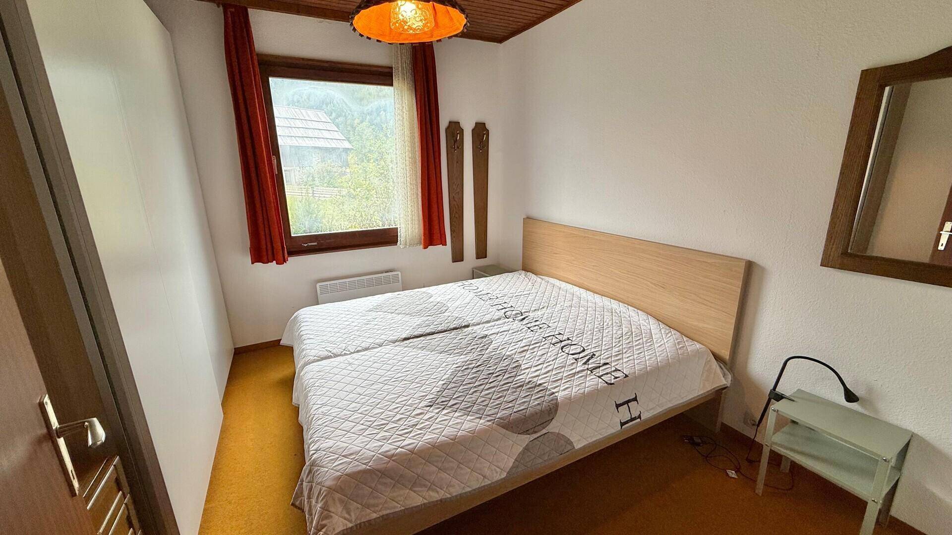 Schlafzimmer mit zwei Einzelbetten, orangefarbenem Teppichboden und Fenster mit Ausblick.