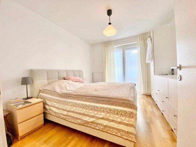 Helles Schlafzimmer mit Doppelbett, Nachttischen und einem Kleiderschrank.