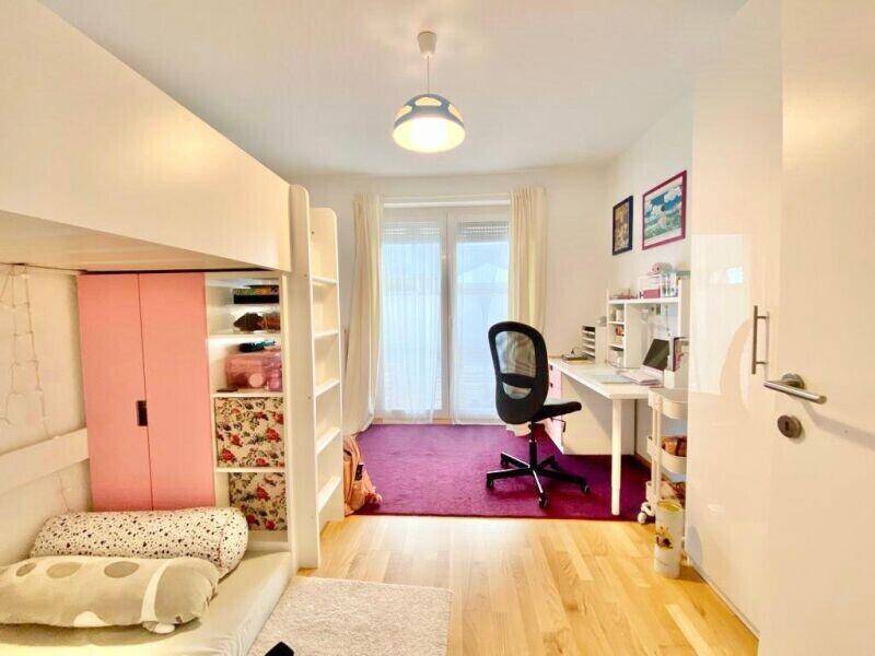 Kinderzimmer mit Hochbett, Schreibtisch und farbenfrohem Teppich, ideal für junge Bewohner.
