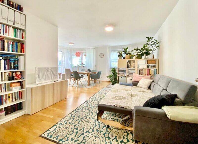 Gemütlicher Wohnbereich mit Sofa, Bücherregalen und Blick auf den angrenzenden Essbereich.
