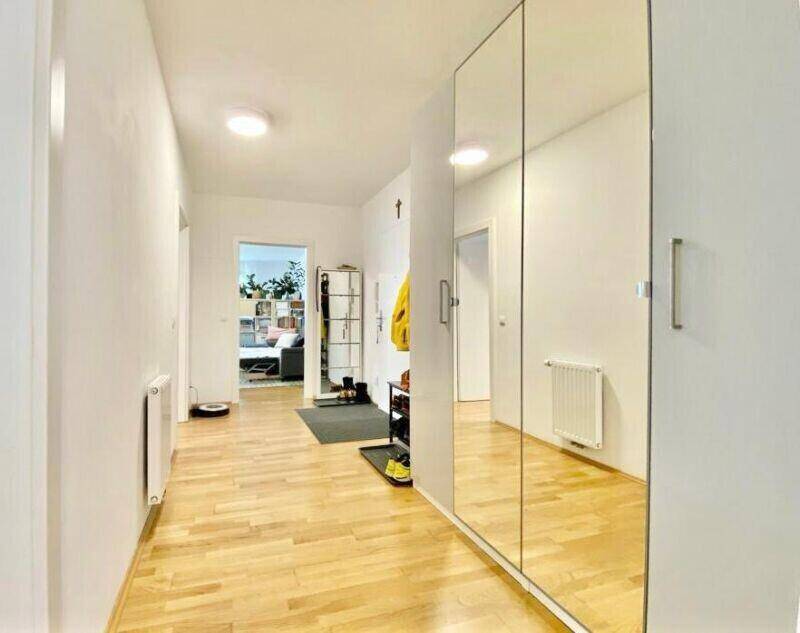 Geräumiger Flur mit Spiegelschränken und hellem Holzboden, der viel Stauraum bietet.