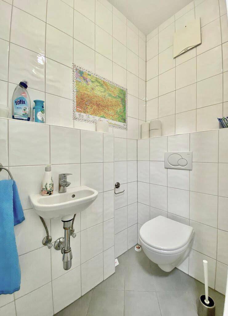 Separates Gäste-WC mit wandhängendem WC und kleinem Handwaschbecken, komplett gefliest.