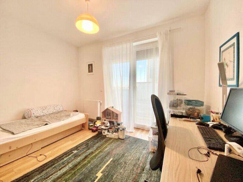 Helles Kinderzimmer mit Einzelbett, Schreibtisch und Zugang zu einem Balkon oder einer Terrasse.