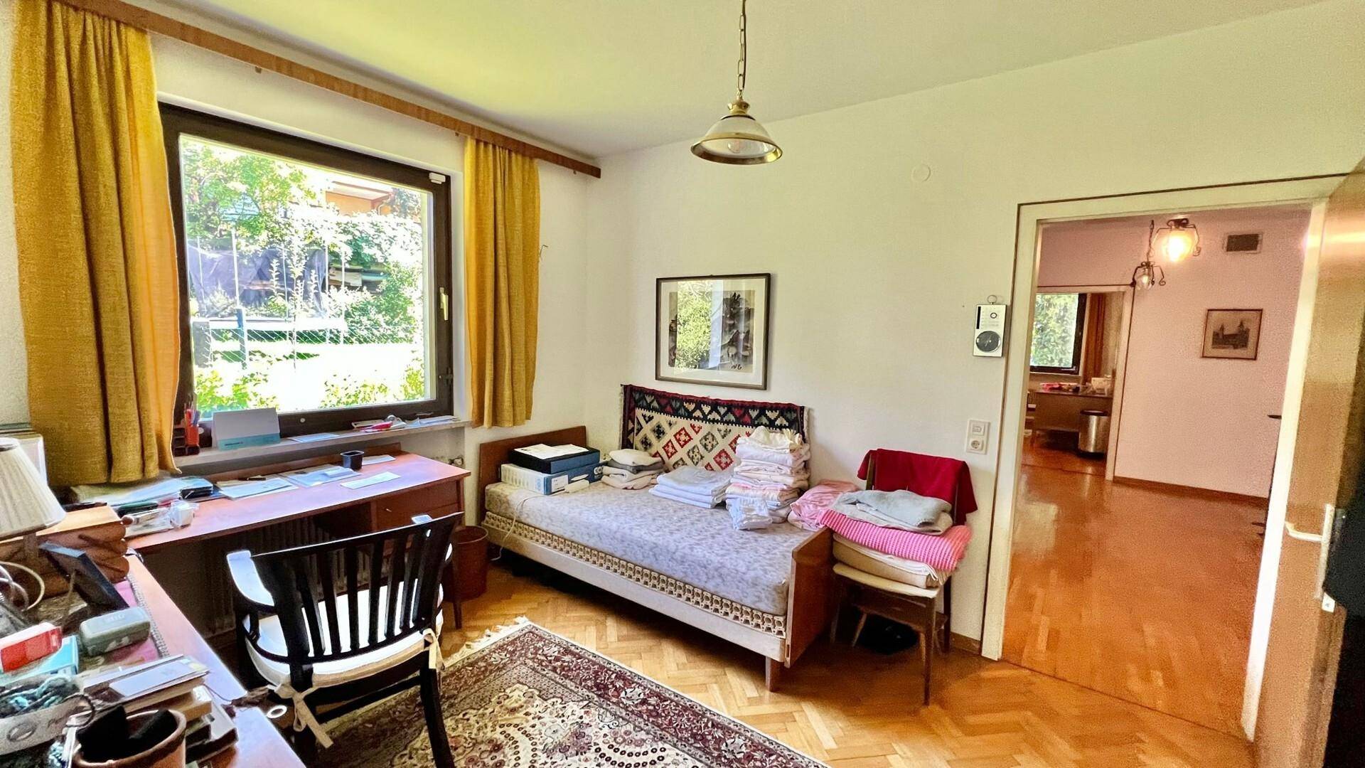 Helles Zimmer mit Parkettboden, Schreibtisch und Blick ins Grüne.