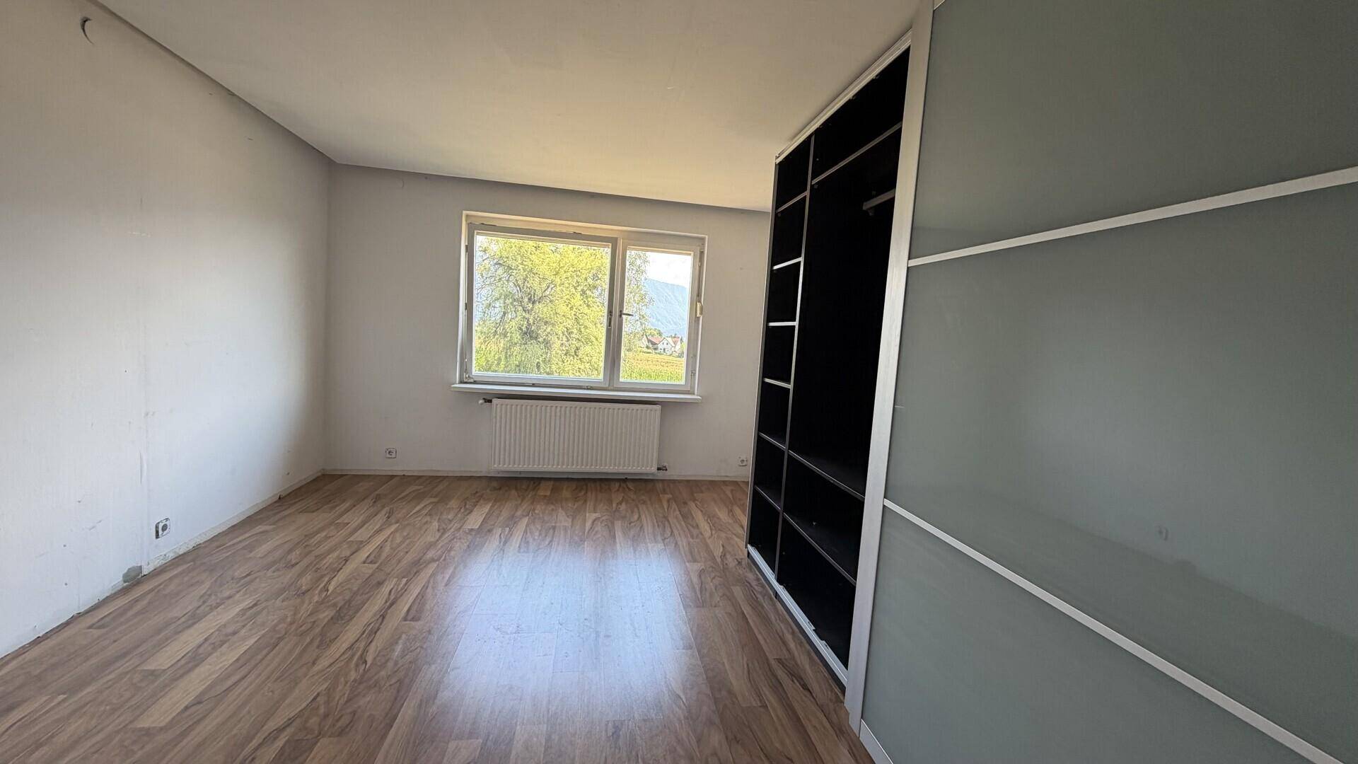 Schlafzimmer mit Holzboden und großem Schrank, hell und geräumig.