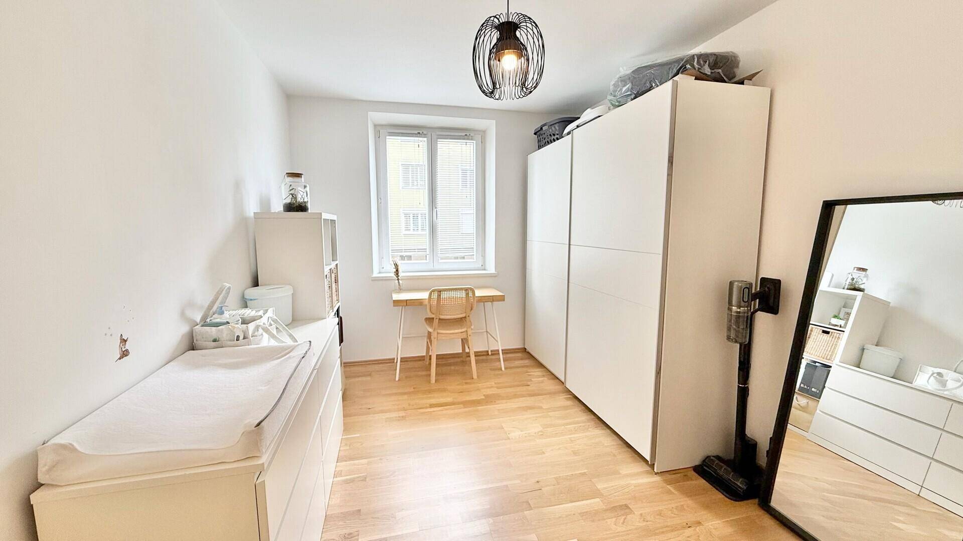 Geräumiges Zimmer mit viel Stauraum, Schreibtisch und hellem Holzboden.