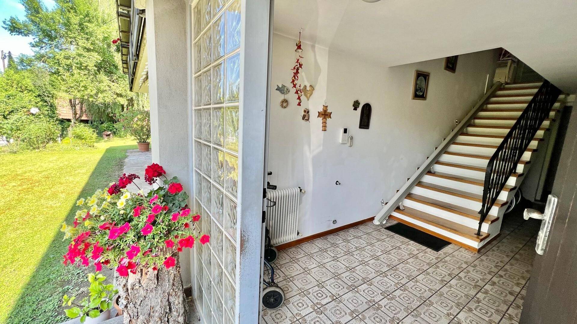 Eingangsbereich mit gefliestem Boden, Treppe und Blick in den Garten.
