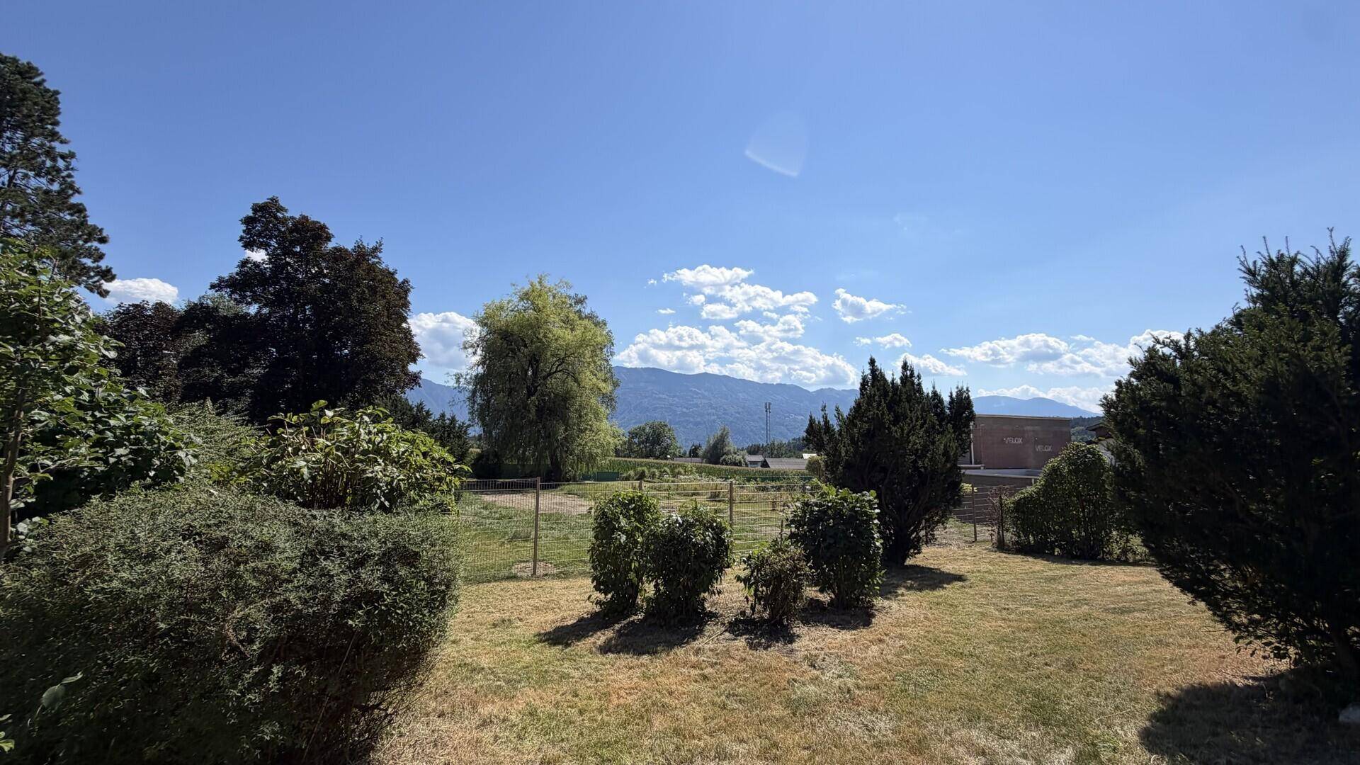 Weitläufiger Gartenbereich mit grüner Wiese und Panoramablick auf die Berge.