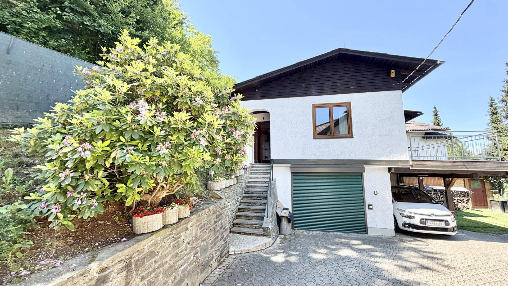 Ansicht des Hauses mit Garage, Außentreppe und gepflegter Bepflanzung im Vorgarten.