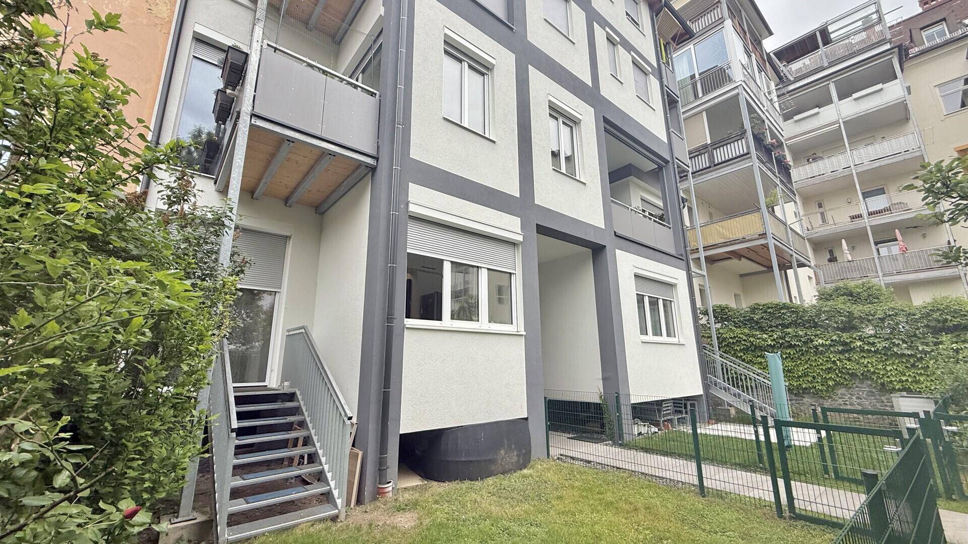Rückseite des Wohnhauses mit mehreren Balkonen und einem begrünten Gartenbereich.