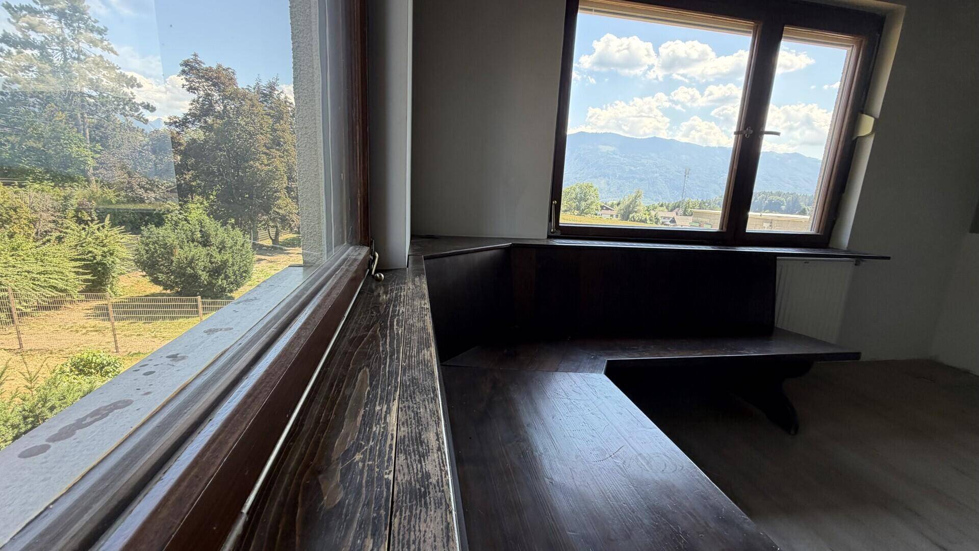Raum mit Holzbänken und großen Fenstern, die einen weiten Blick bieten.