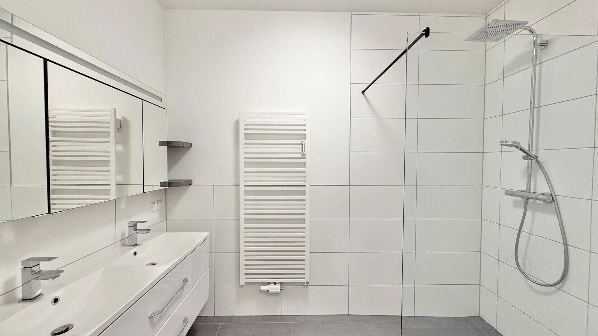 Modernes Badezimmer mit Doppelwaschbecken, großer begehbarer Dusche und Handtuchheizkörper.