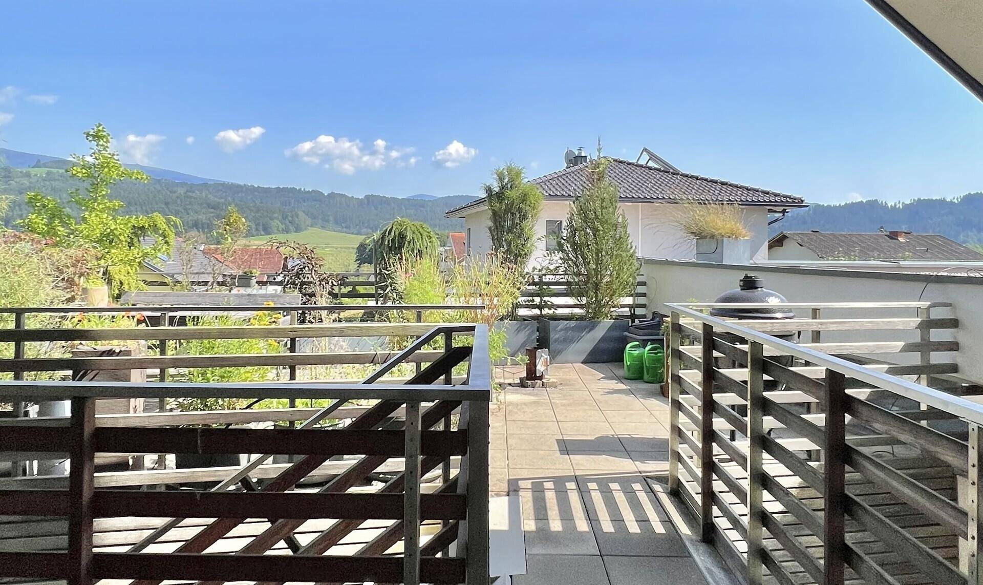 Geräumige Dachterrasse mit Holzboden und weitem Blick auf die umliegende Berglandschaft.
