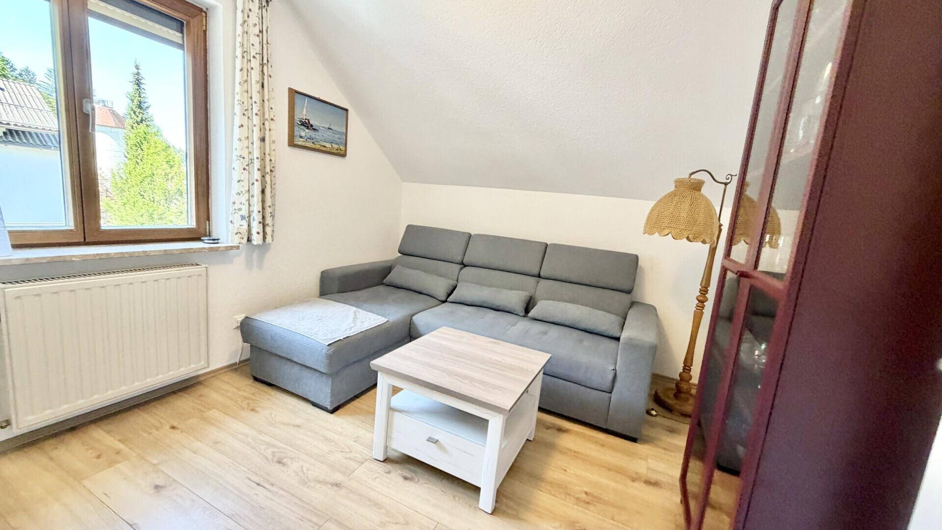 Gemütlicher Wohnbereich im Dachgeschoss mit Sofa, Couchtisch und Holzboden.