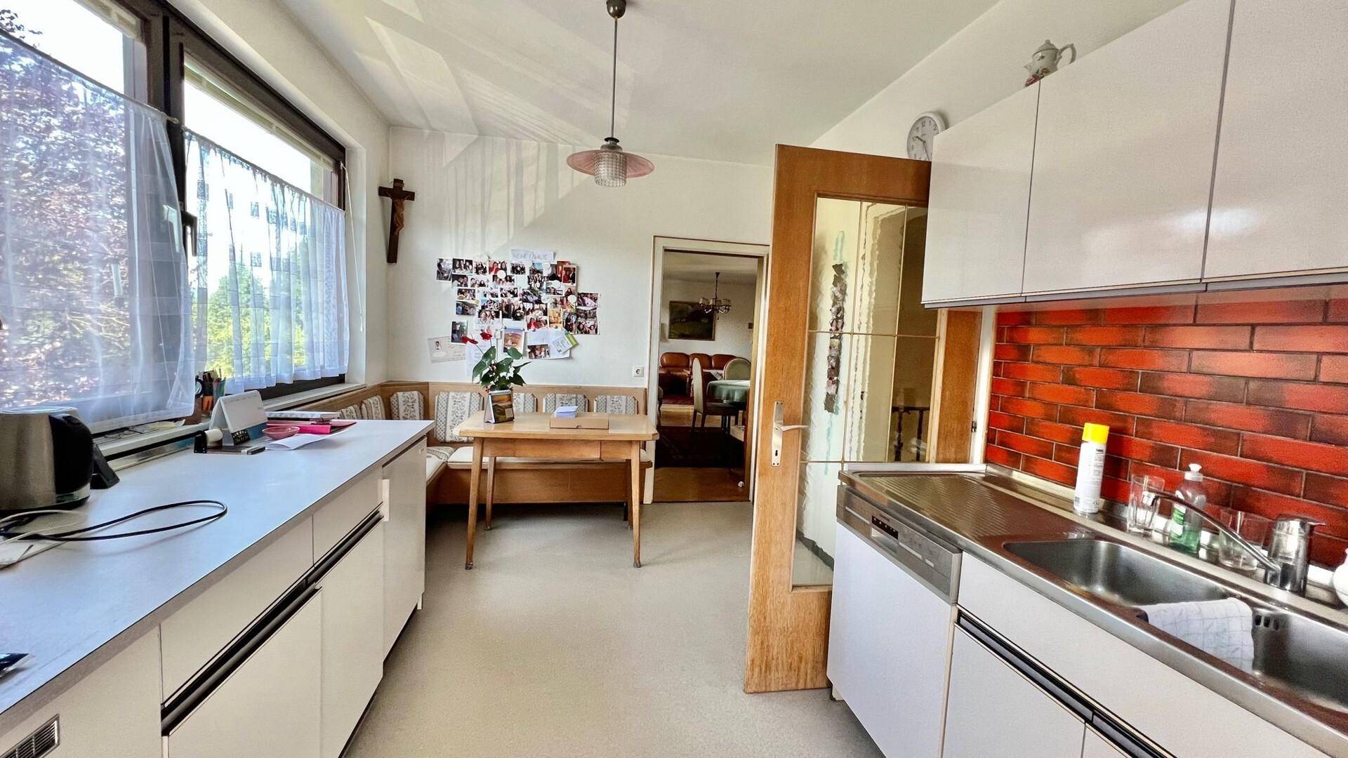 Funktionale Küche mit Essbereich, weißen Schränken und Fenster mit Ausblick.