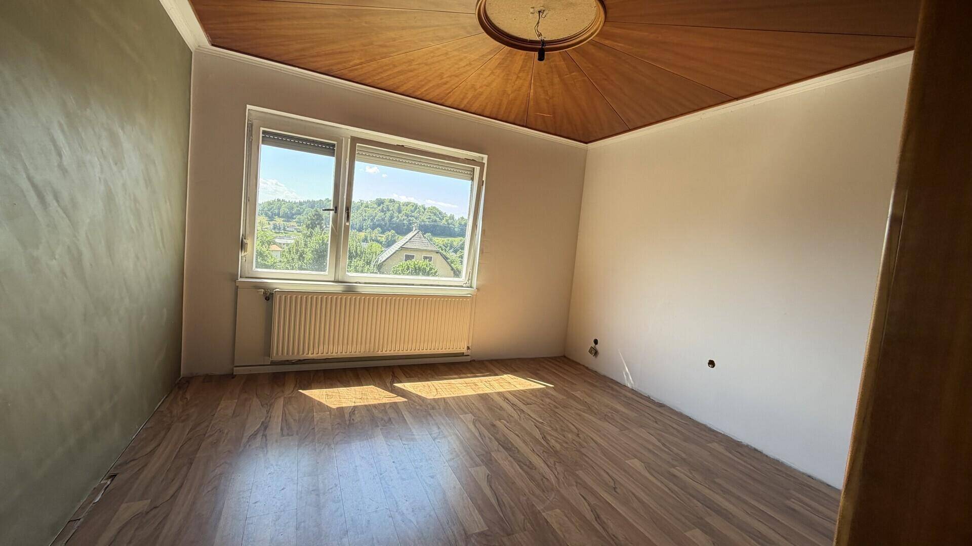 Schlafzimmer mit Holzboden und dekorativer Holzdecke, hell und freundlich.