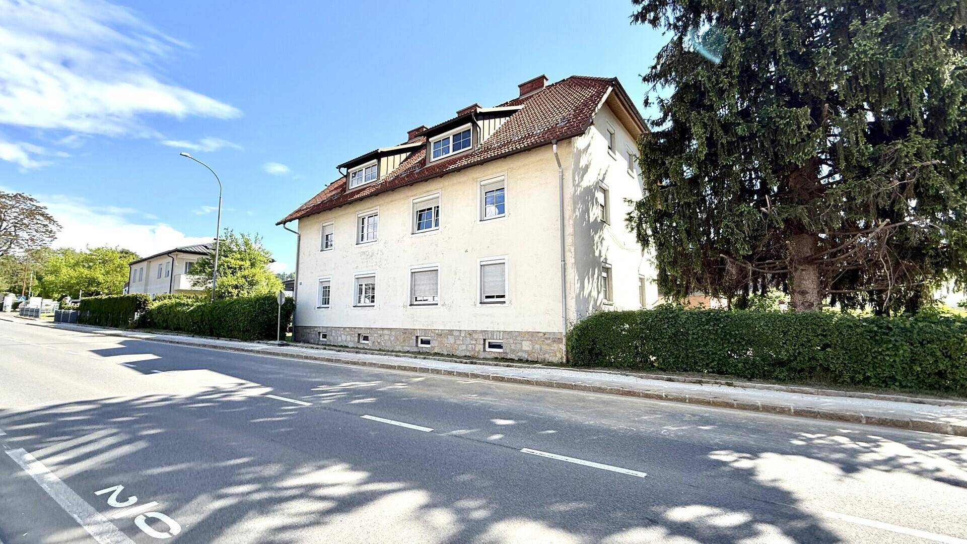 Ansicht des Wohnhauses von der Straße aus mit gepflegter Hecke und altem Baumbestand.