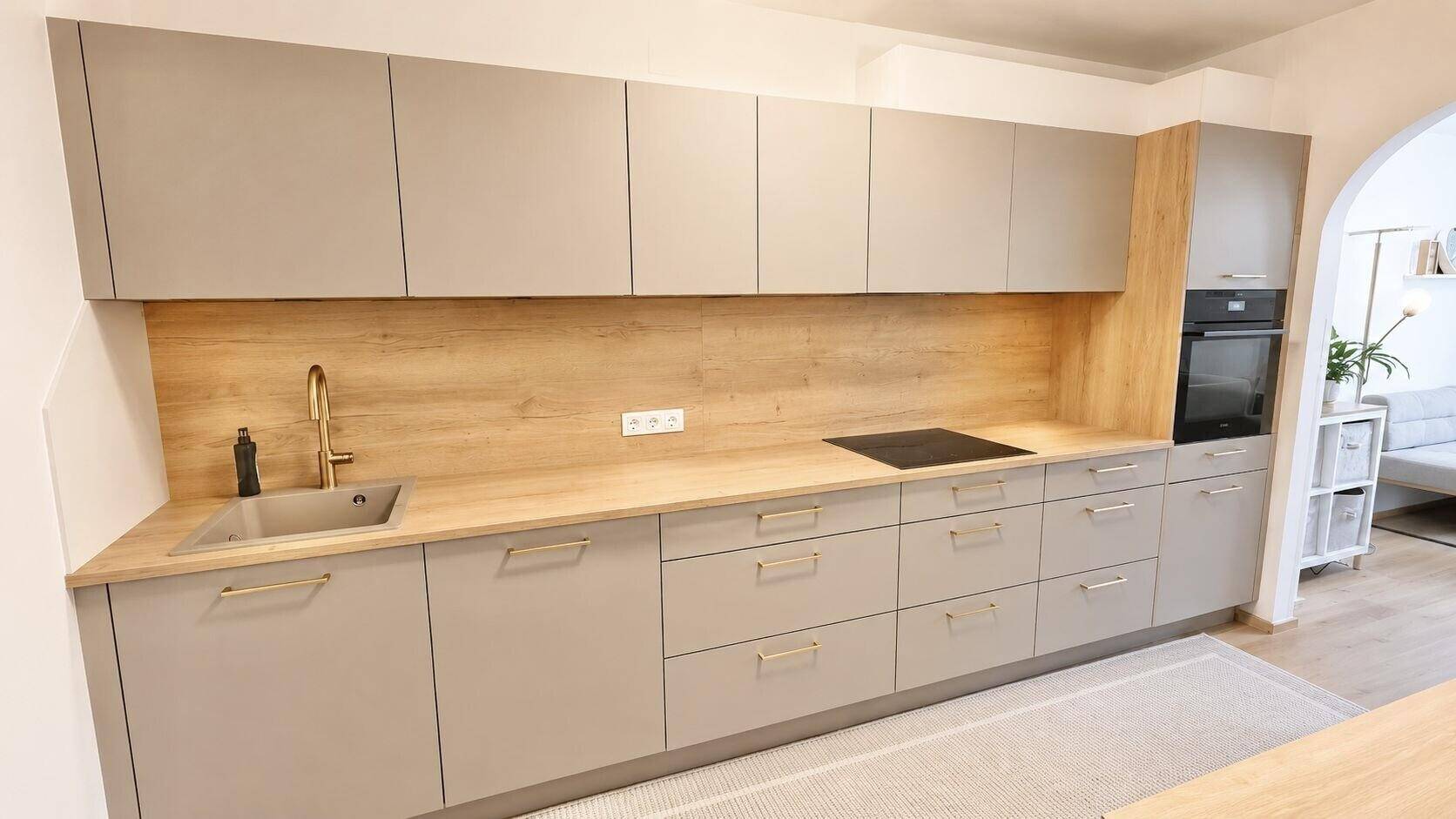 Moderne Küche mit grauen Schränken, Holzoptik-Arbeitsplatte und integriertem Backofen.