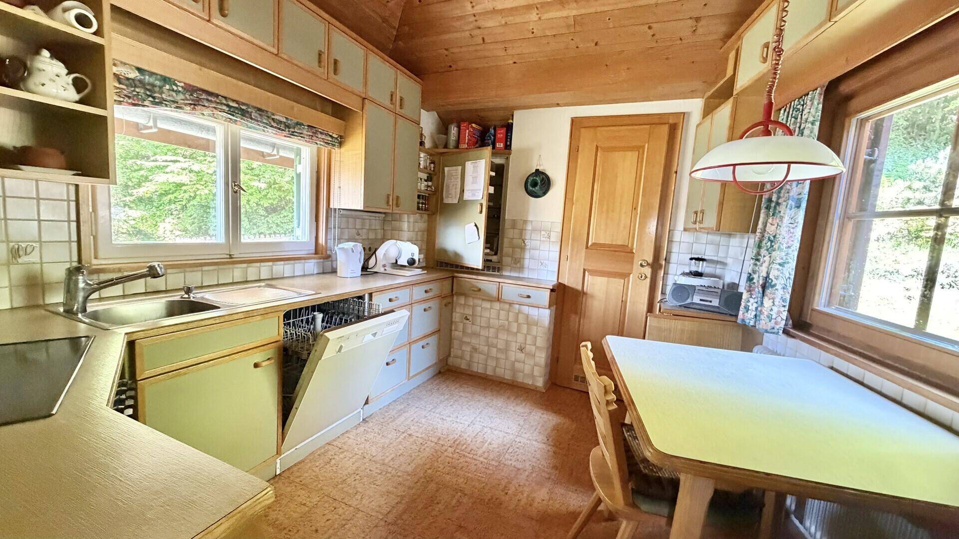 Funktionale Küche im Landhausstil mit Essbereich, Holzdecke und Blick ins Grüne.