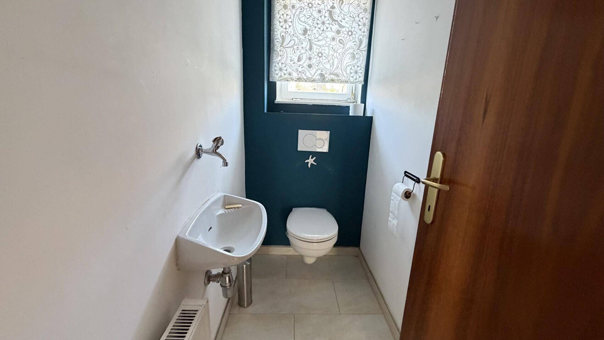 Kleines Gäste-WC mit Waschbecken und Wand-WC, modern gestaltet.