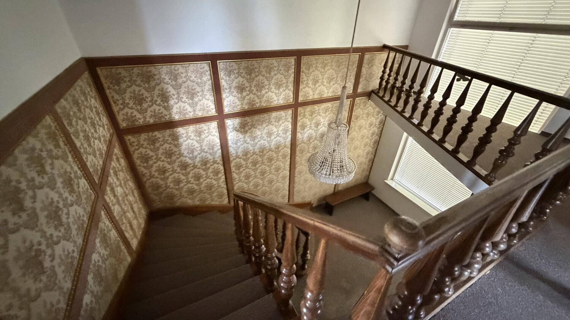 Treppenhaus mit Holzgeländer und gemusterter Tapete, klassischer Stil.