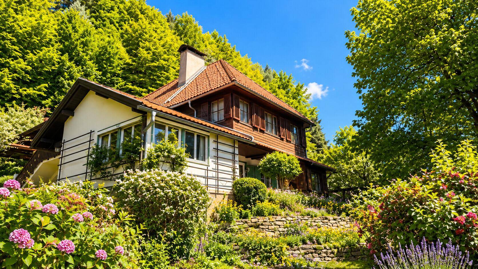 Gepflegter Garten mit blühenden Sträuchern und Terrassenmauern vor dem Landhaus.