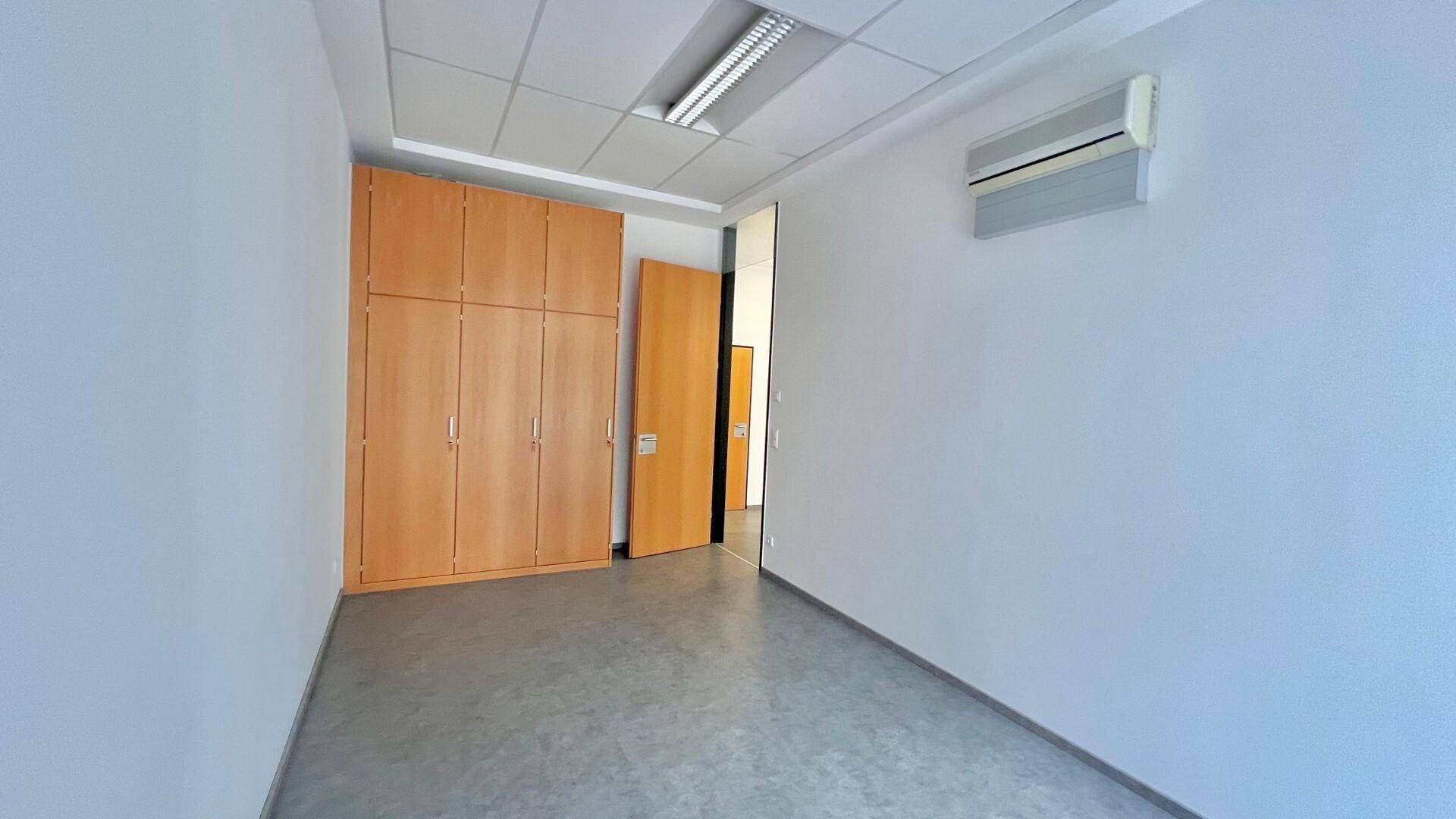Büro mit großem Einbauschrank, Klimaanlage und schlichtem Bodenbelag, ideal für Stauraum.