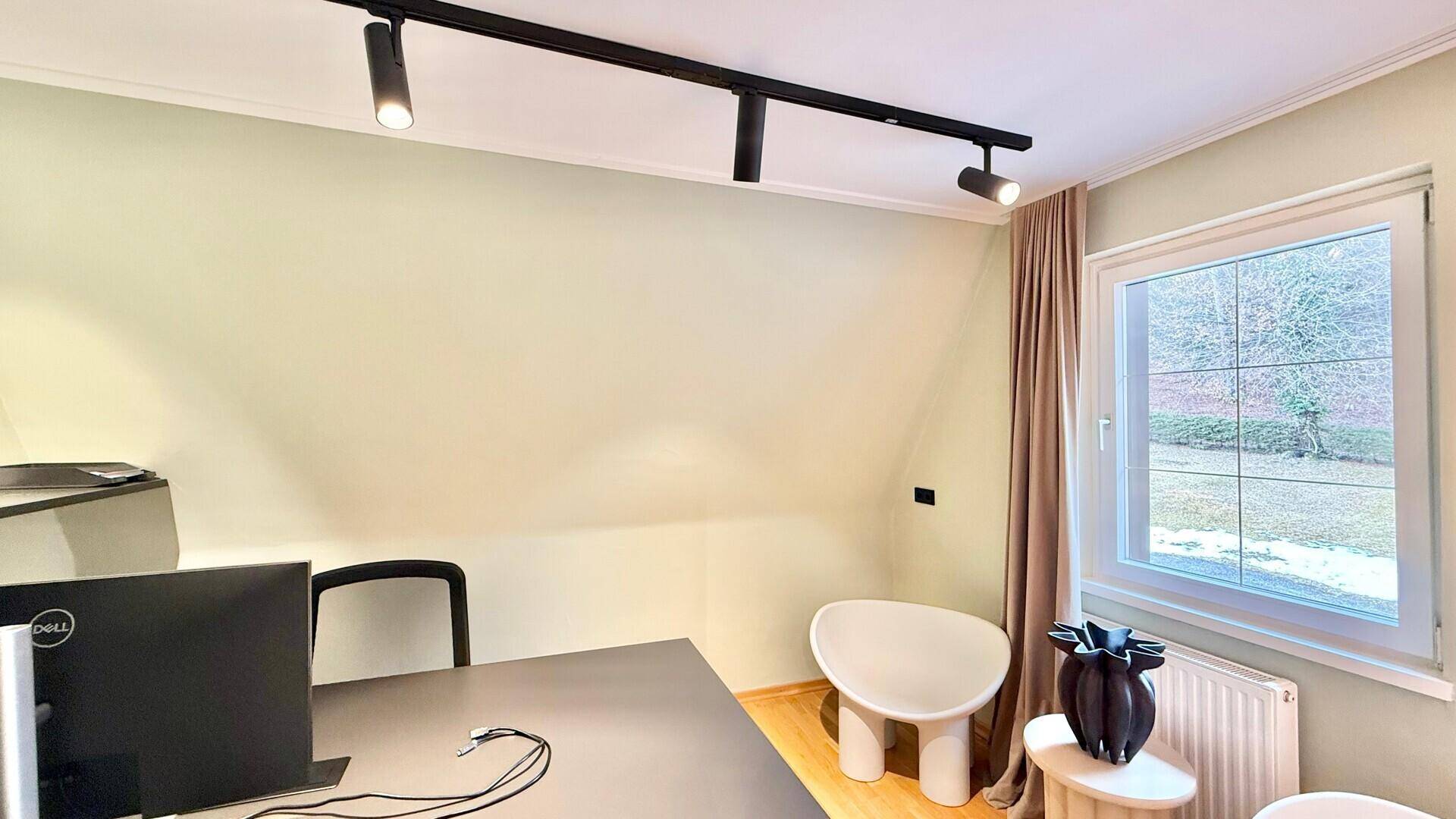 Ruhiges Arbeitszimmer mit Schreibtisch, Dachschräge und Fenster mit Blick ins Grüne.
