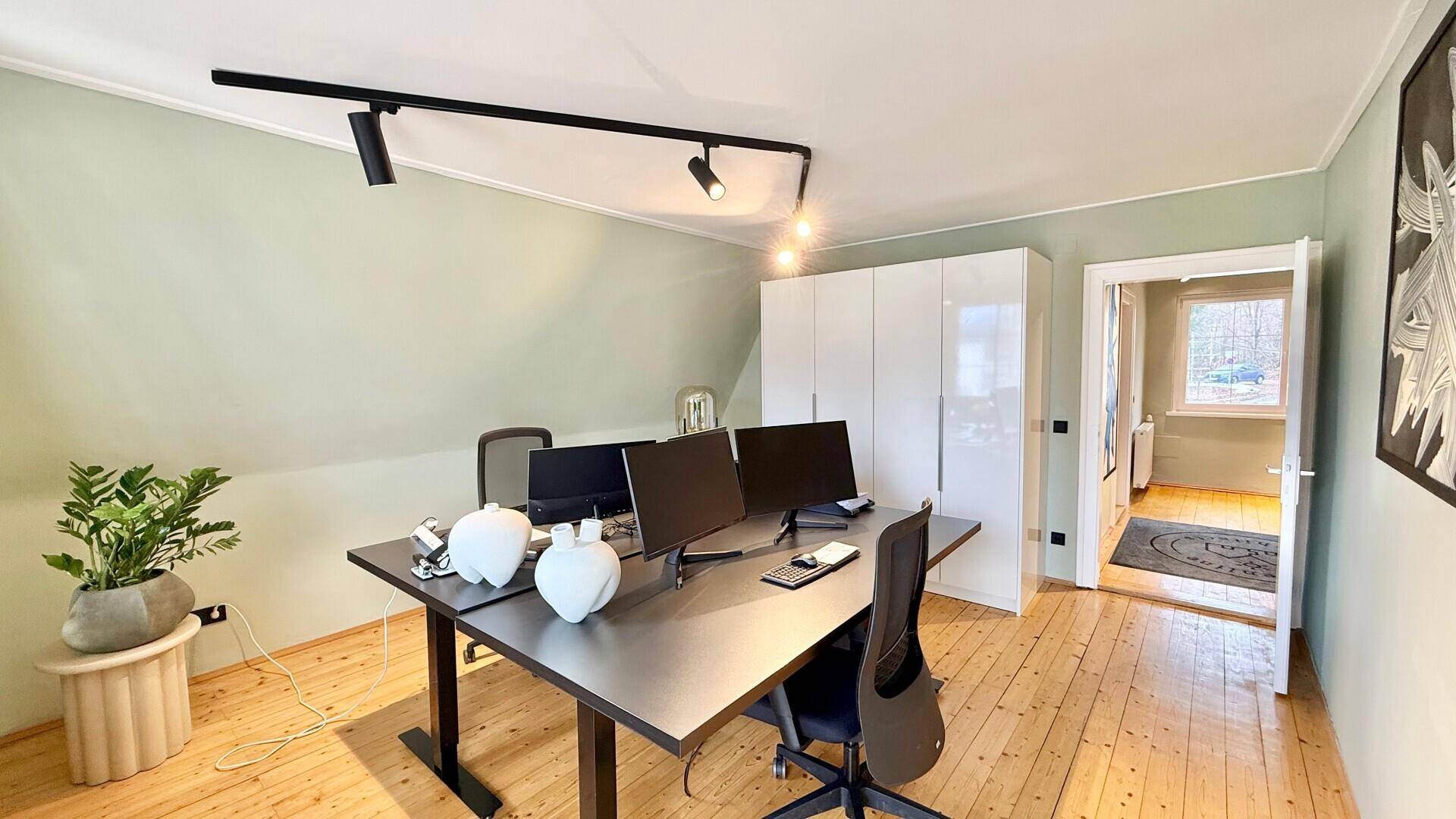 Funktionales Büro mit Schreibtisch, weißem Kleiderschrank und Holzboden.