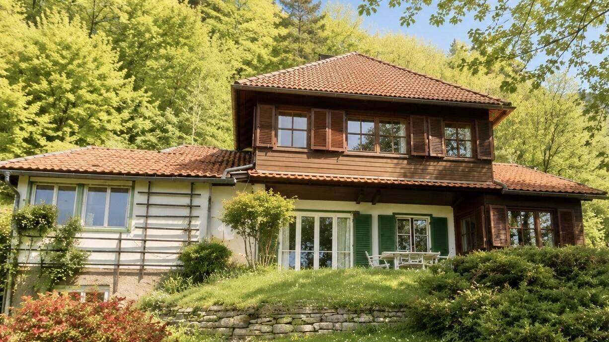 Charmantes Landhaus mit traditionellem Ziegeldach und Holzfensterläden, eingebettet in die Natur.