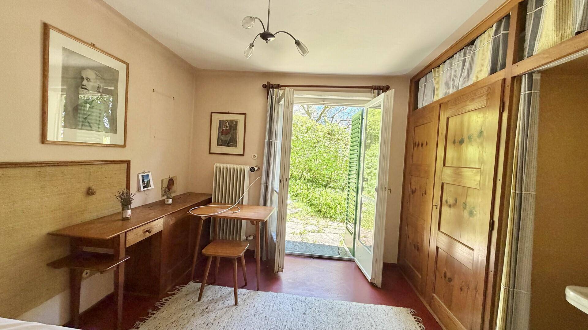 Schlafzimmer mit Holzboden, Zugang zum Garten und rustikalen Holzschränken.