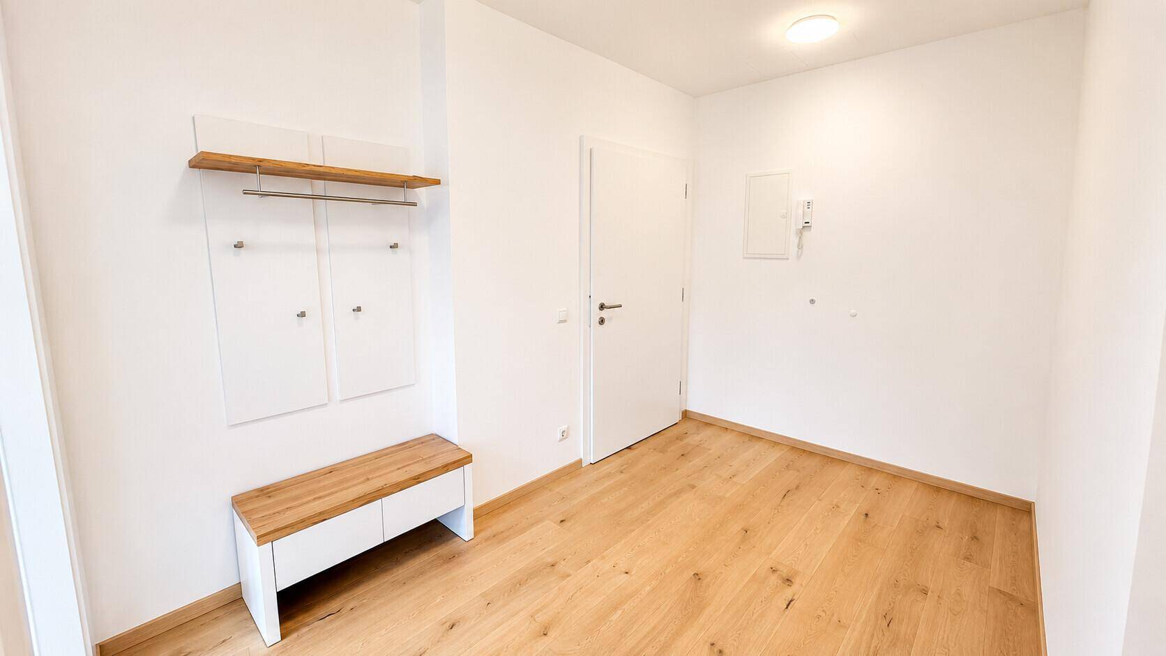 Eingangsbereich mit praktischer Garderobe und Sitzbank, ausgestattet mit hellem Holzboden.