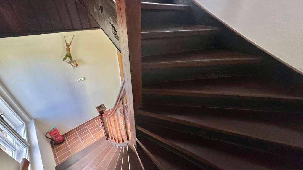 Dunkle Holztreppe mit Geländer, die die verschiedenen Ebenen des Hauses verbindet.