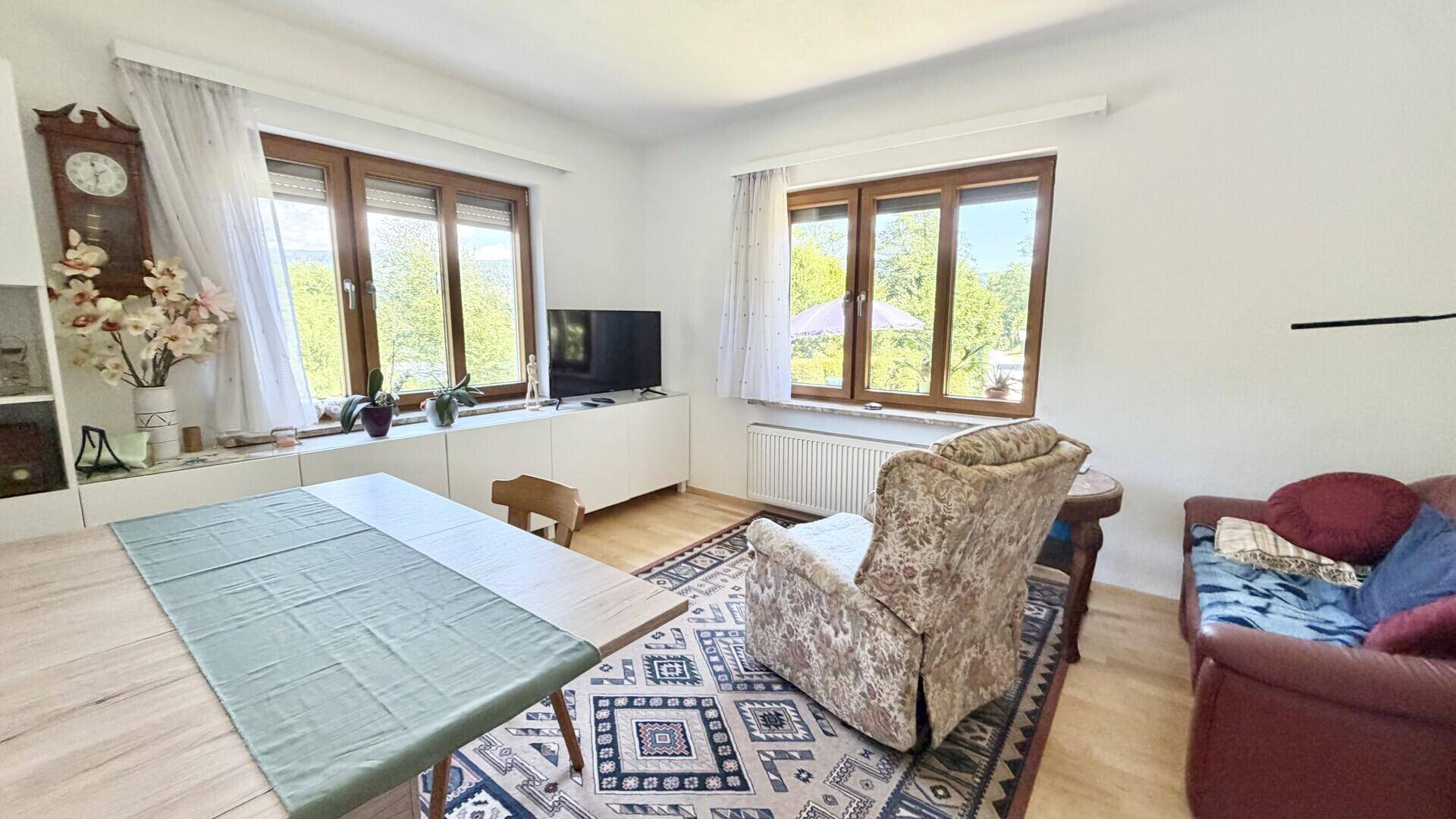 Gemütliches Wohnzimmer mit traditionellem Teppich, Esstisch und Fenstern mit weitem Ausblick.