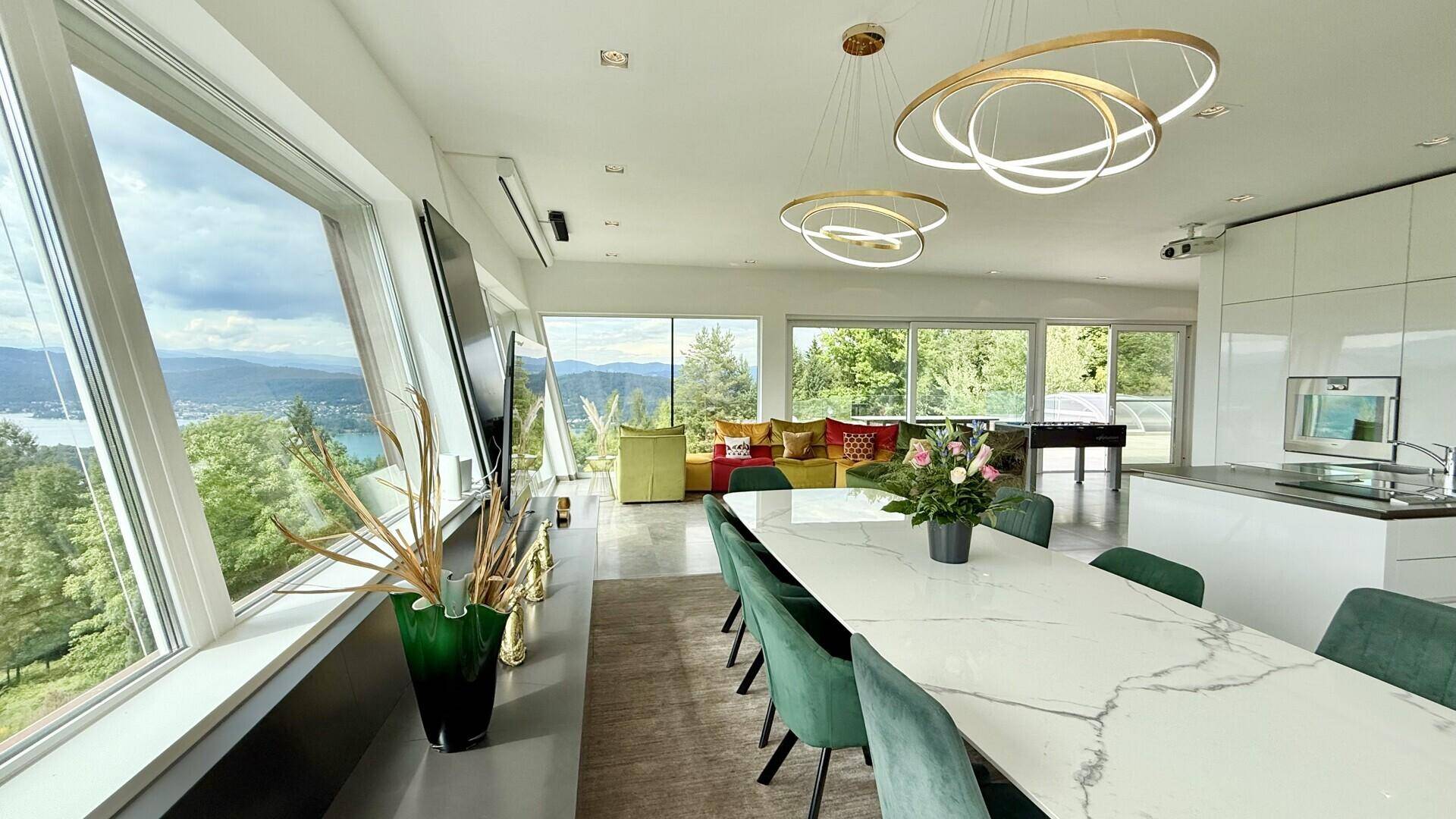 Offener Wohn- und Essbereich mit elegantem Esstisch, modernen Leuchten und Panoramablick auf den See.